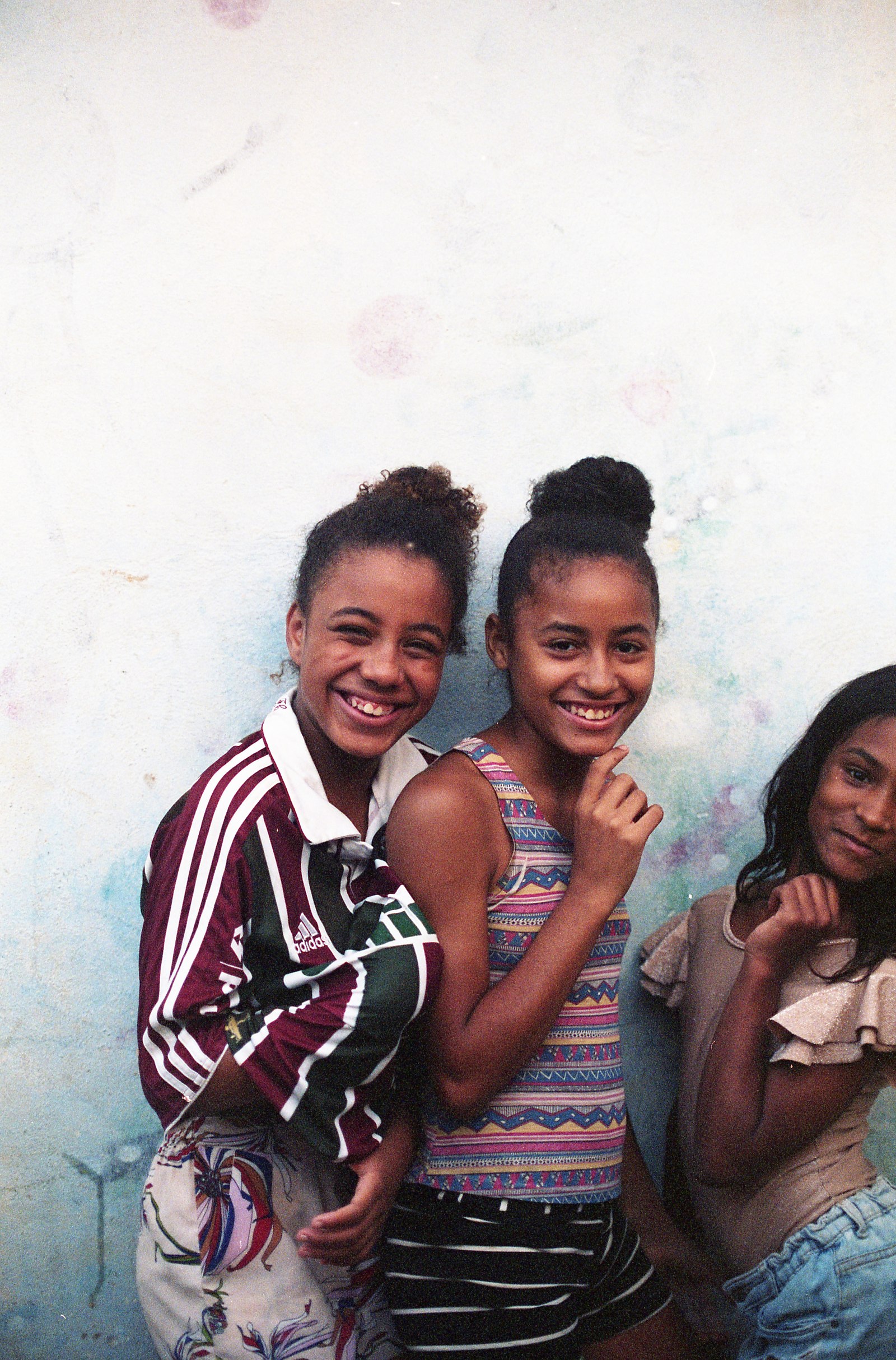 trois filles sourient contre un mur blanc