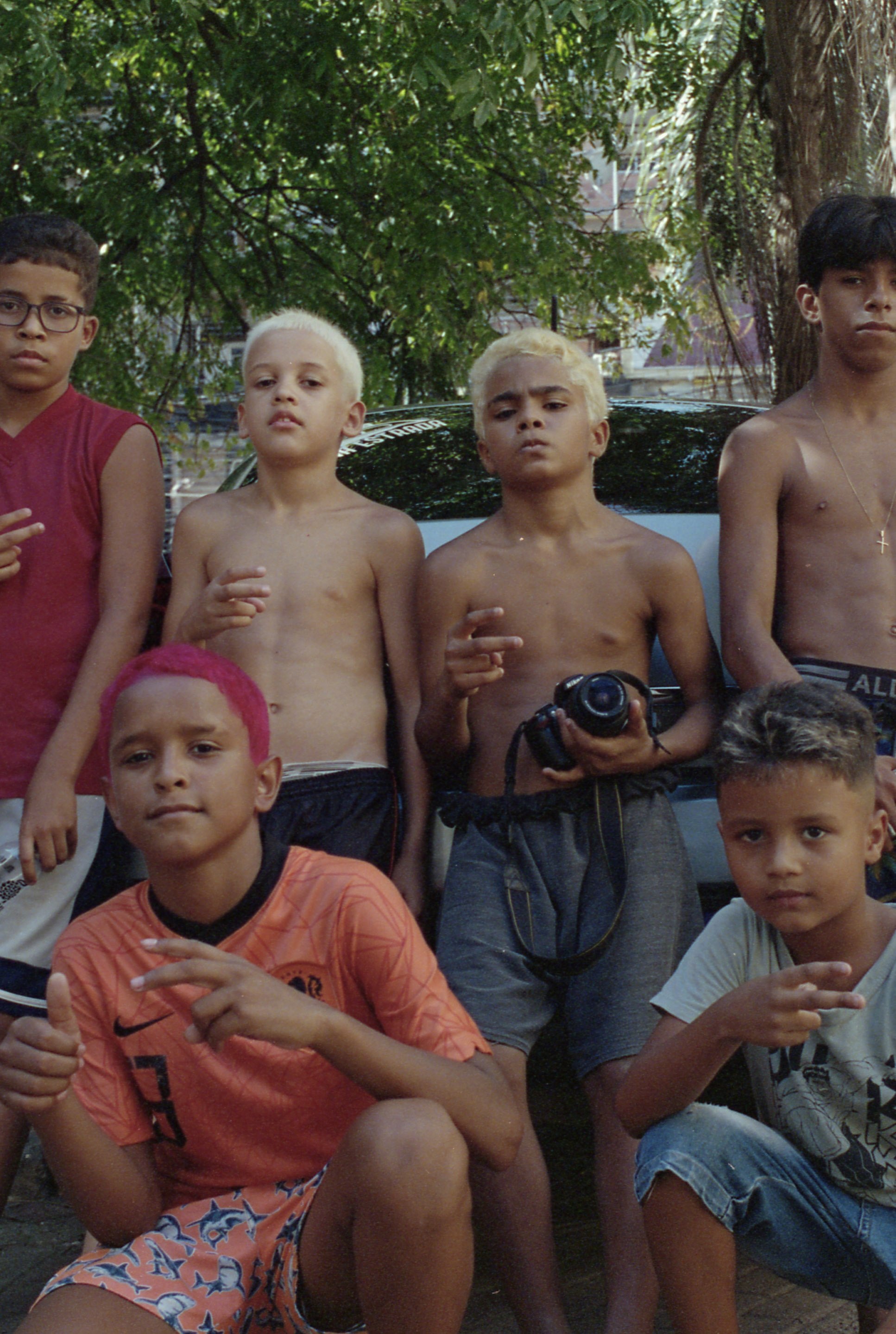 un groupe de garçons aux cheveux décolorés, l’un tient un appareil photo
