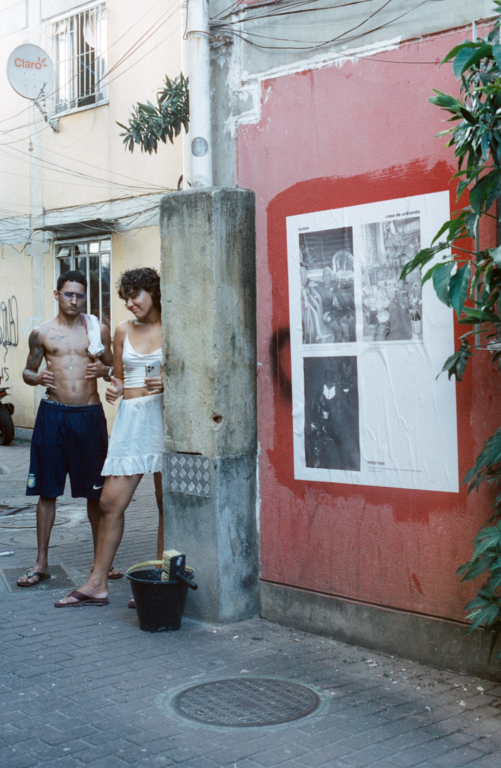 deux jeunes regardent une affiche collée sur un mur rouge
