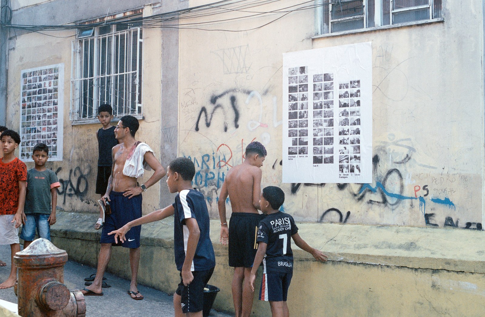 enfants et jeunes devant un mur couvert d’affiches et de graffitis, Rua 4